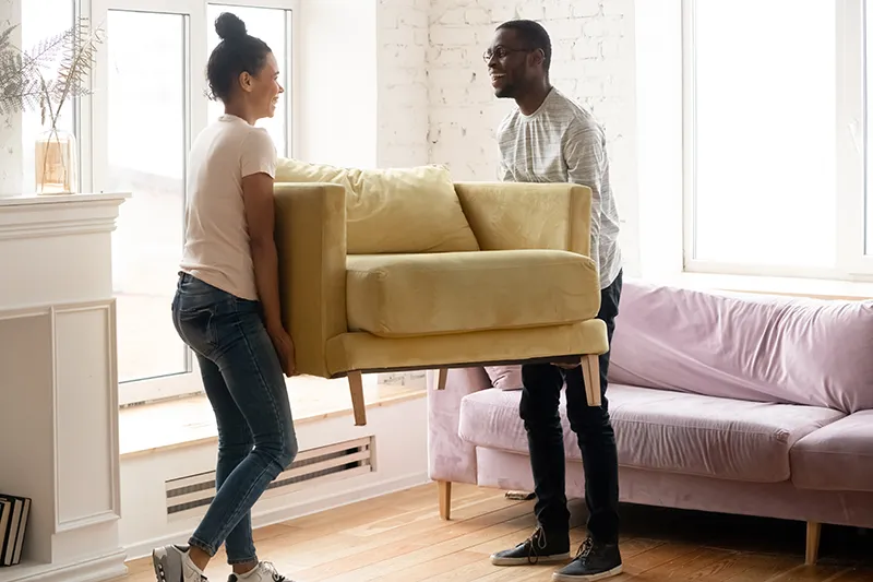 Couple moving furniture before hardwood installation | Jordans Flooring